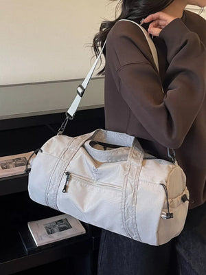 Light gray nylon travel bag with zippered pockets and adjustable strap.