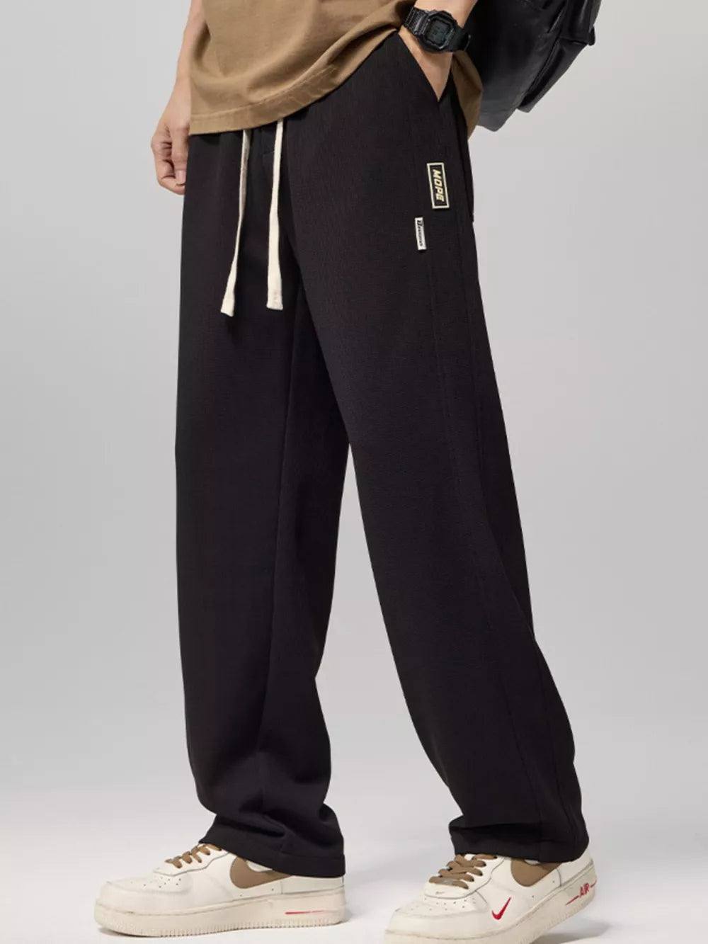 Relaxed fit black drawstring sweatpants with white laces and a small logo patch.