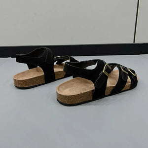 Black suede crossover buckle cork sandals with adjustable straps.