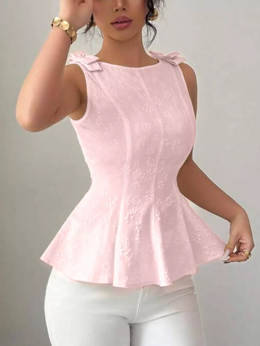 Pink sleeveless peplum tank top with bow shoulder details and floral texture.