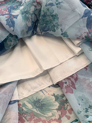 Floral ruffle hem mini dress with a light blue floral print and white lining.