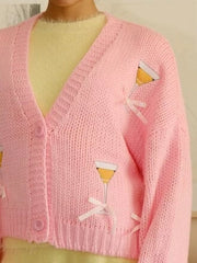 Pink knit cardigan with cocktail glass appliques and bow accents, button-up front.