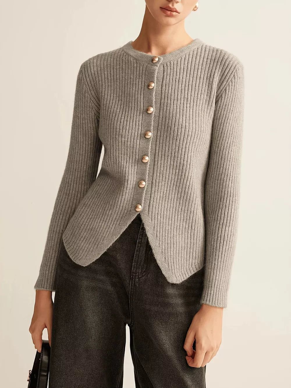 Grey ribbed knit cardigan with crew neck, gold buttons, and asymmetrical hem.