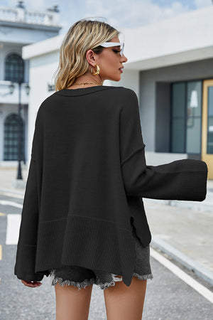 Black acrylic knit sweater with flared sleeves and slit hem detail