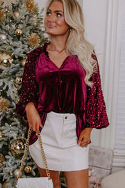 Velvet blouse with sequin bell sleeves and ruffled neckline in red.