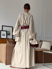 Beige cotton maxi dress with tie neck, ruffled long sleeves, and side slits.