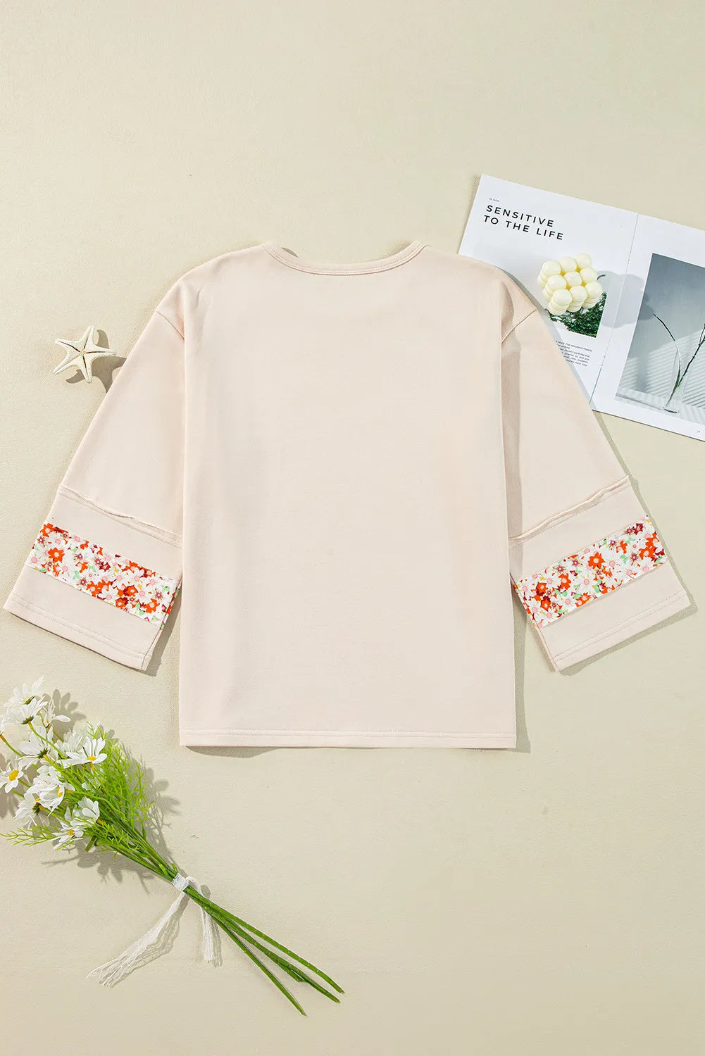 Ivory sweatshirt with floral appliqué raglan sleeves and crew neck.