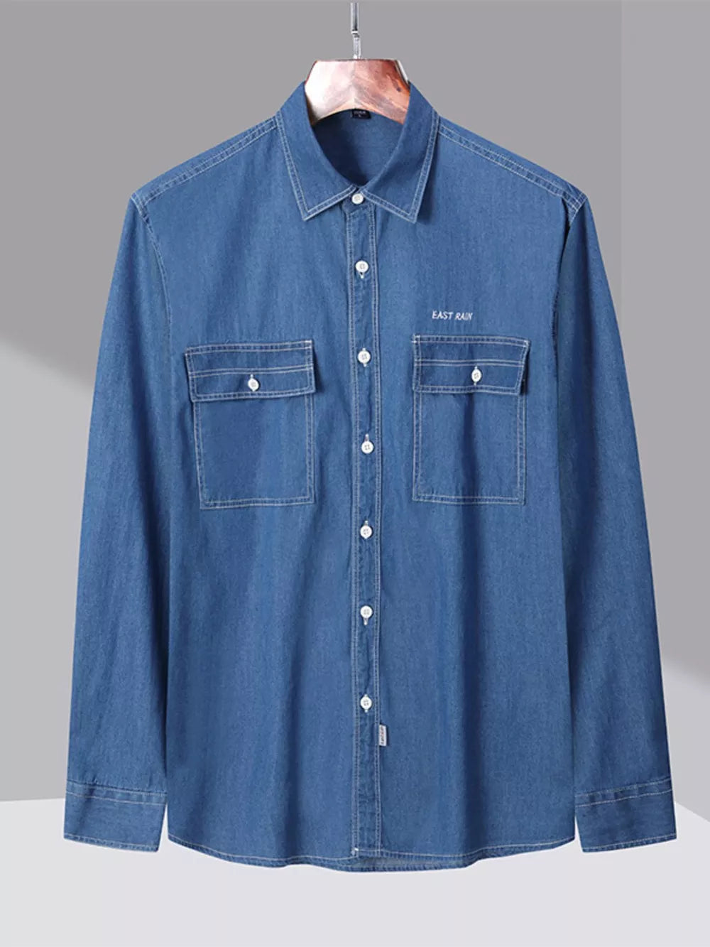 Blue denim button-up shirt with chest pockets and embroidered text detail.