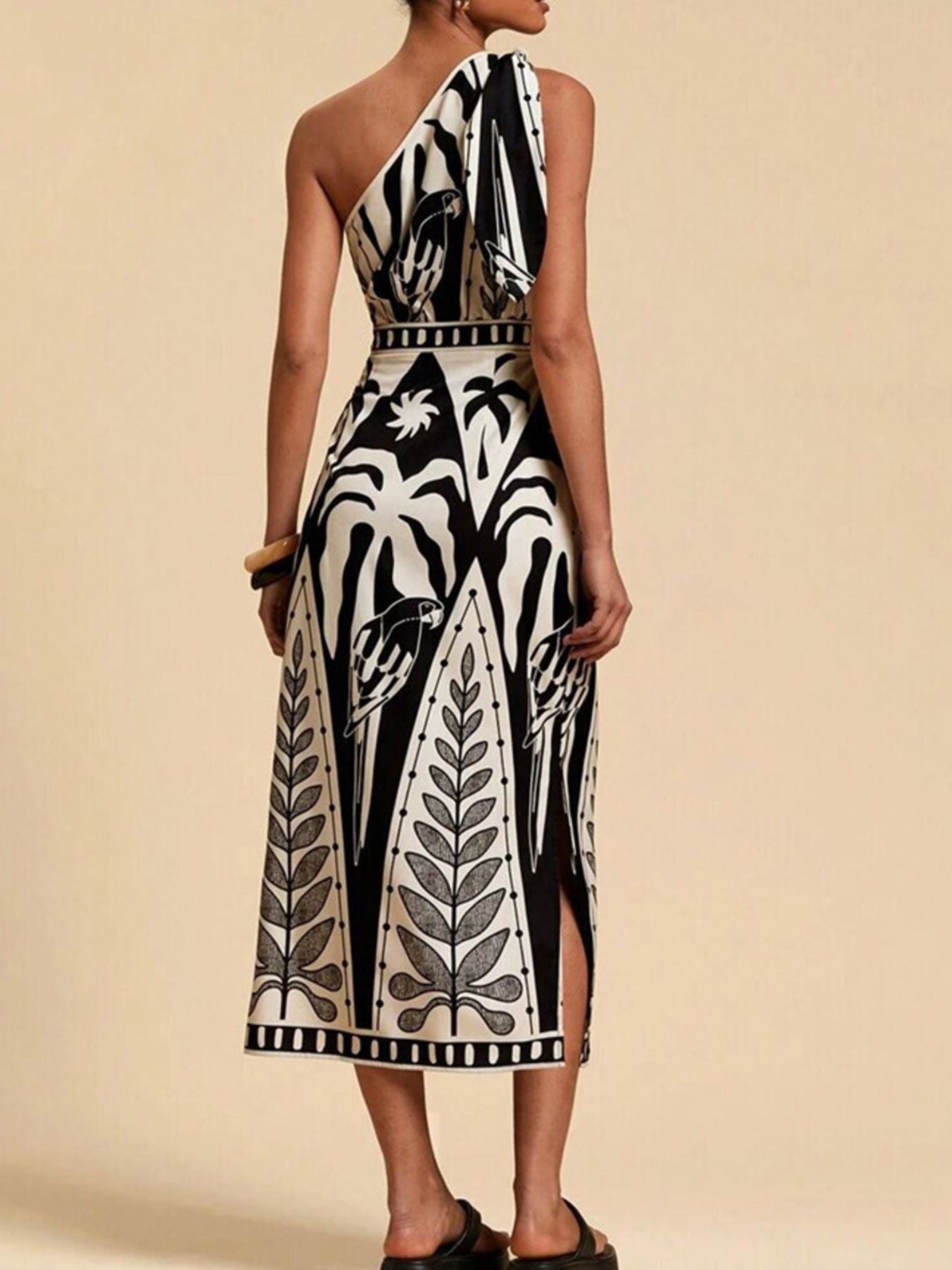 Black and white tropical print one-shoulder midi dress with defined waist and side slits.