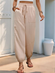 Textured tan cargo pants with drawstring waist and elastic cuffs, featuring multiple pockets.