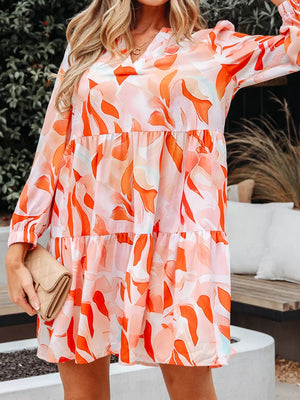 Tiered mini dress with abstract print, V-neck, long sleeves, and flowy skirt.
