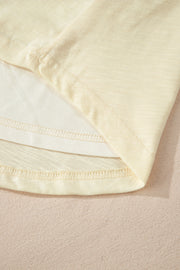 Pastel yellow embroidered poet sleeve blouse hem detail with layered fabric and stitching.