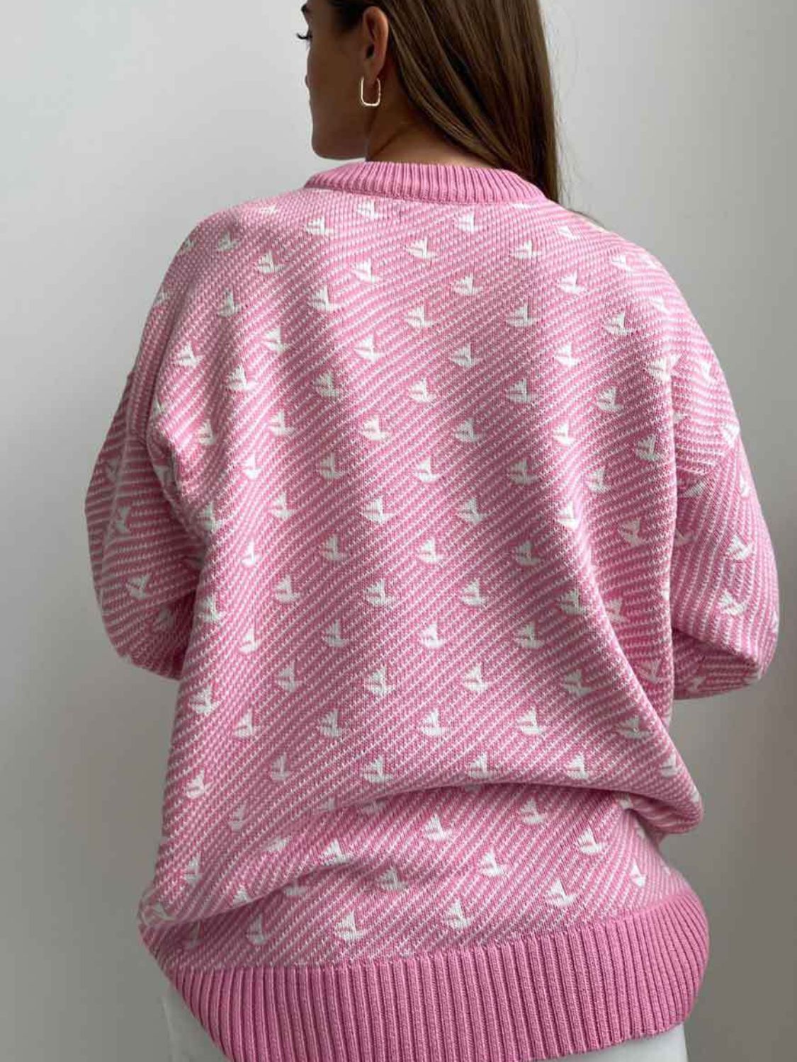Blush pink knit sweater with allover white sailboat jacquard pattern and ribbed trim.