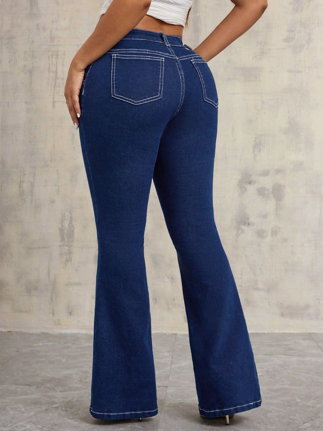 Dark wash denim flare jeans with contrast stitching and pocket detail.
