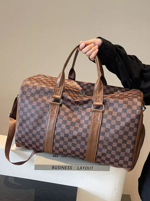 Chic checkered travel bag with brown leather accents and adjustable strap.