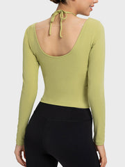 Yellow-green ribbed long sleeve active top with cutout shoulders and halter tie detail