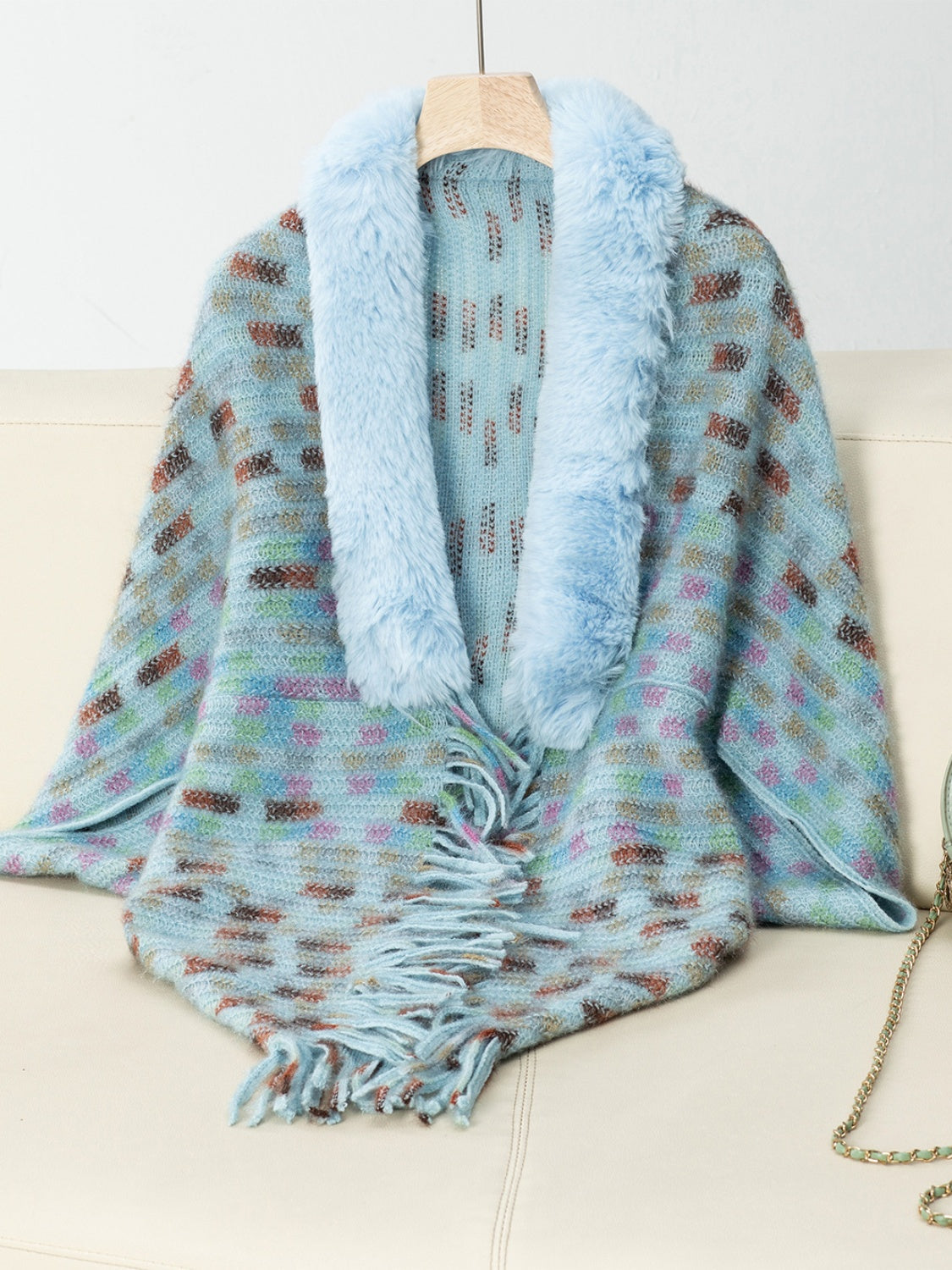 Pastel blue knit poncho with plaid pattern, faux fur collar, and fringe detail.