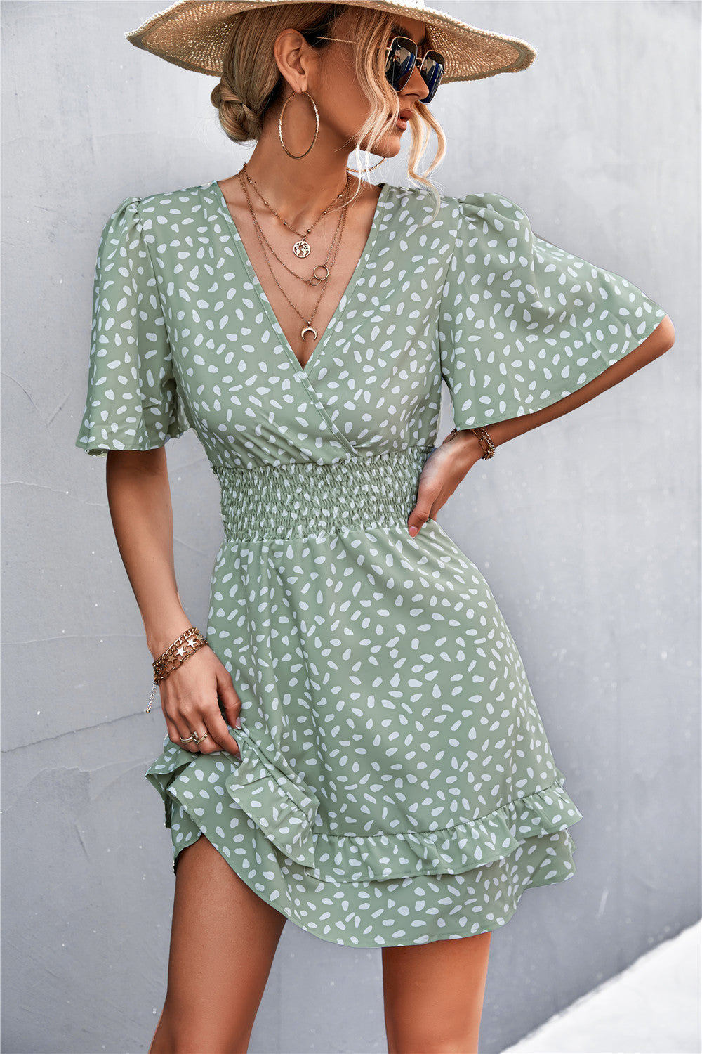 Gum Leaf smocked waist mini dress with white speckle print, flutter sleeves, and ruffled hem.