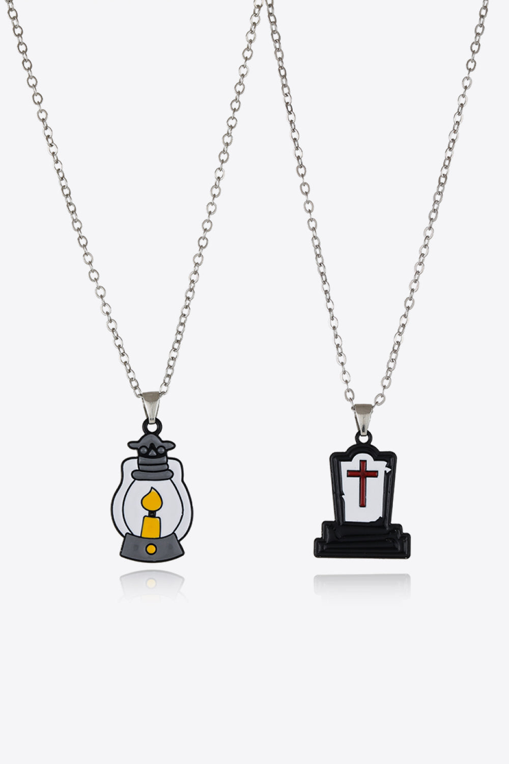 Spooky Season enamel pendant necklaces, one with a lantern, one with a tombstone and cross.