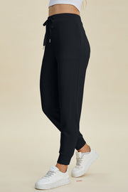 Black joggers with drawstring waist and cuffed ankles.