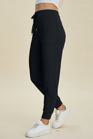 Black joggers with drawstring waist and cuffed ankles.