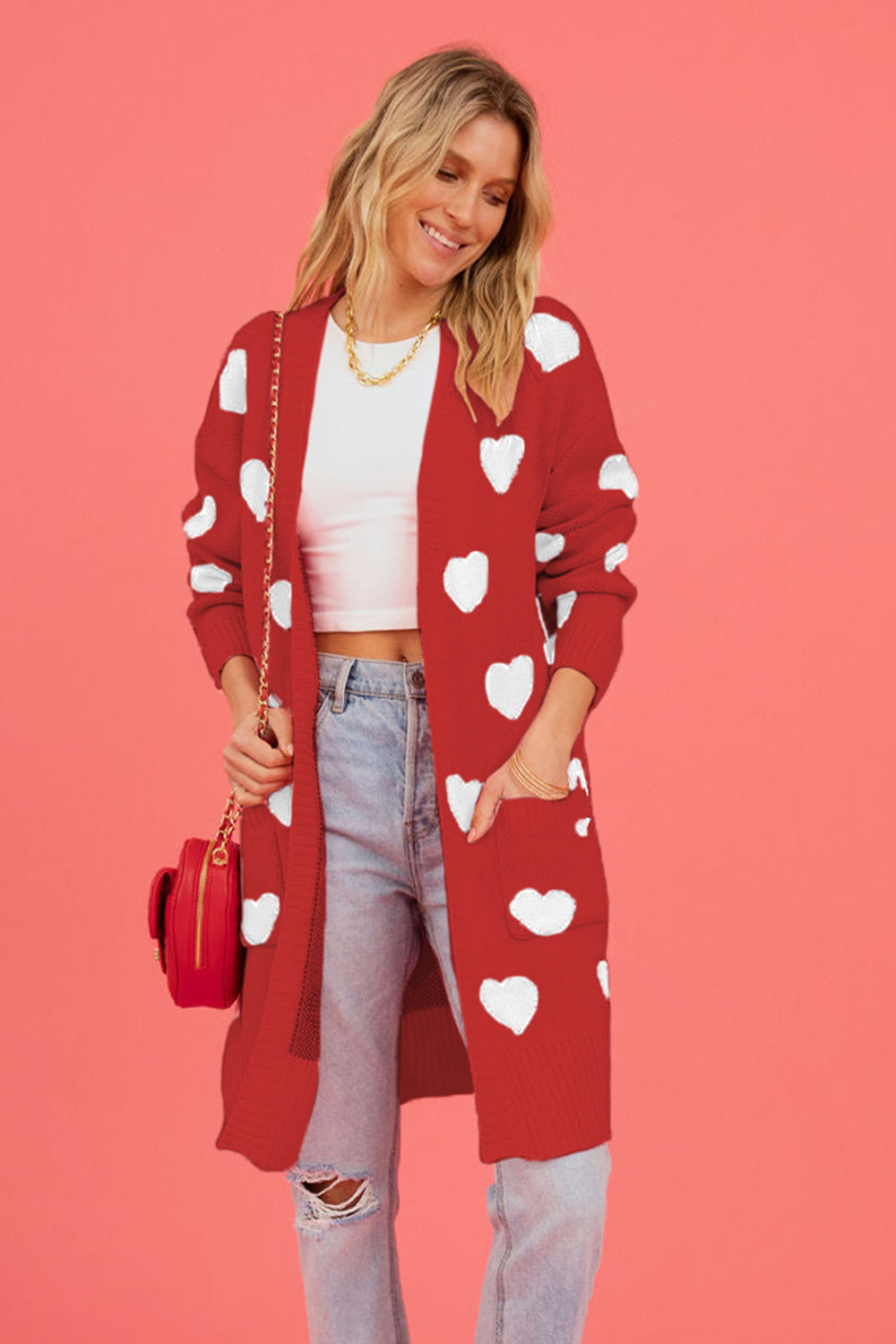 Red acrylic longline cardigan with white heart motif and pockets.