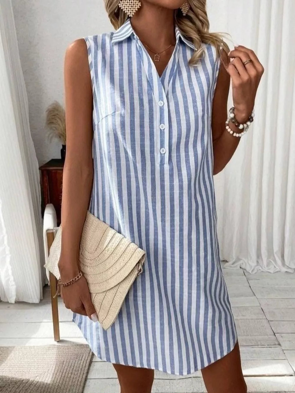 Light blue striped sleeveless collared shirt dress with button front and above-knee length.
