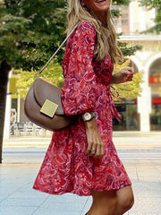 Red paisley print balloon sleeve dress with a tie waist and ruffled hem.