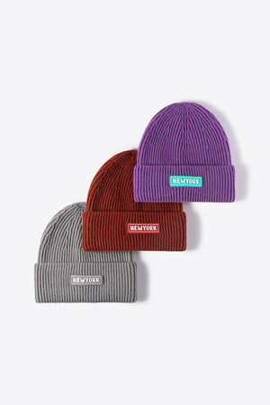Ribbed acrylic beanies in purple, rust, and gray, each with a New York patch detail.