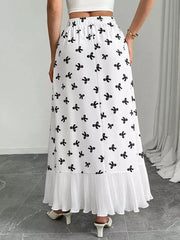 White maxi skirt with black bow print and pleated hem.