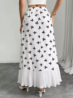 White maxi skirt with black bow print and pleated hem.