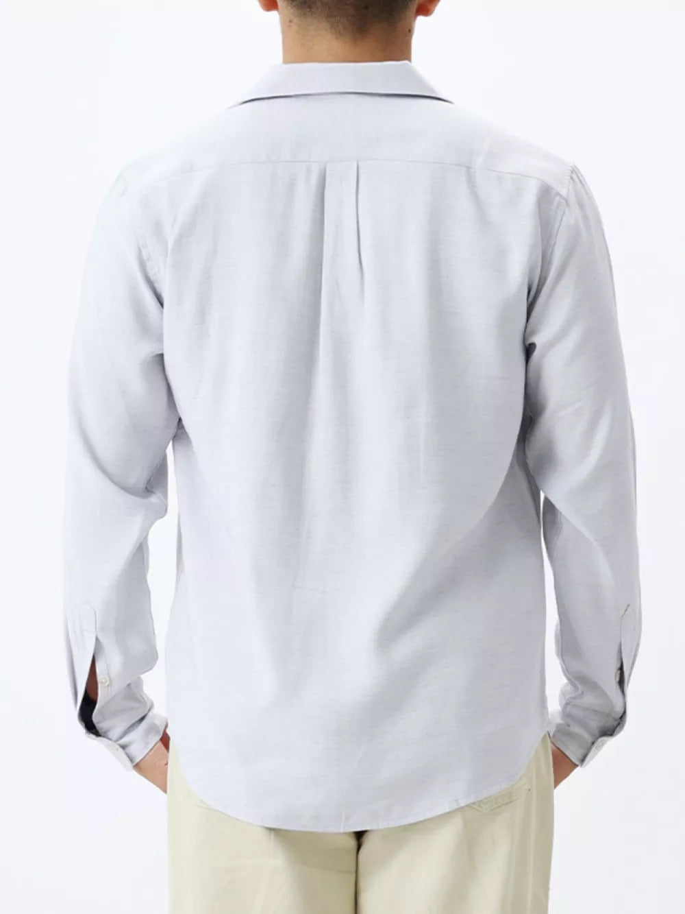 Relaxed camp collar button-up shirt in light blue with back pleats and buttoned cuffs.