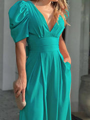 Teal romper with puff sleeves, deep V-neck, cinched waist and pockets.