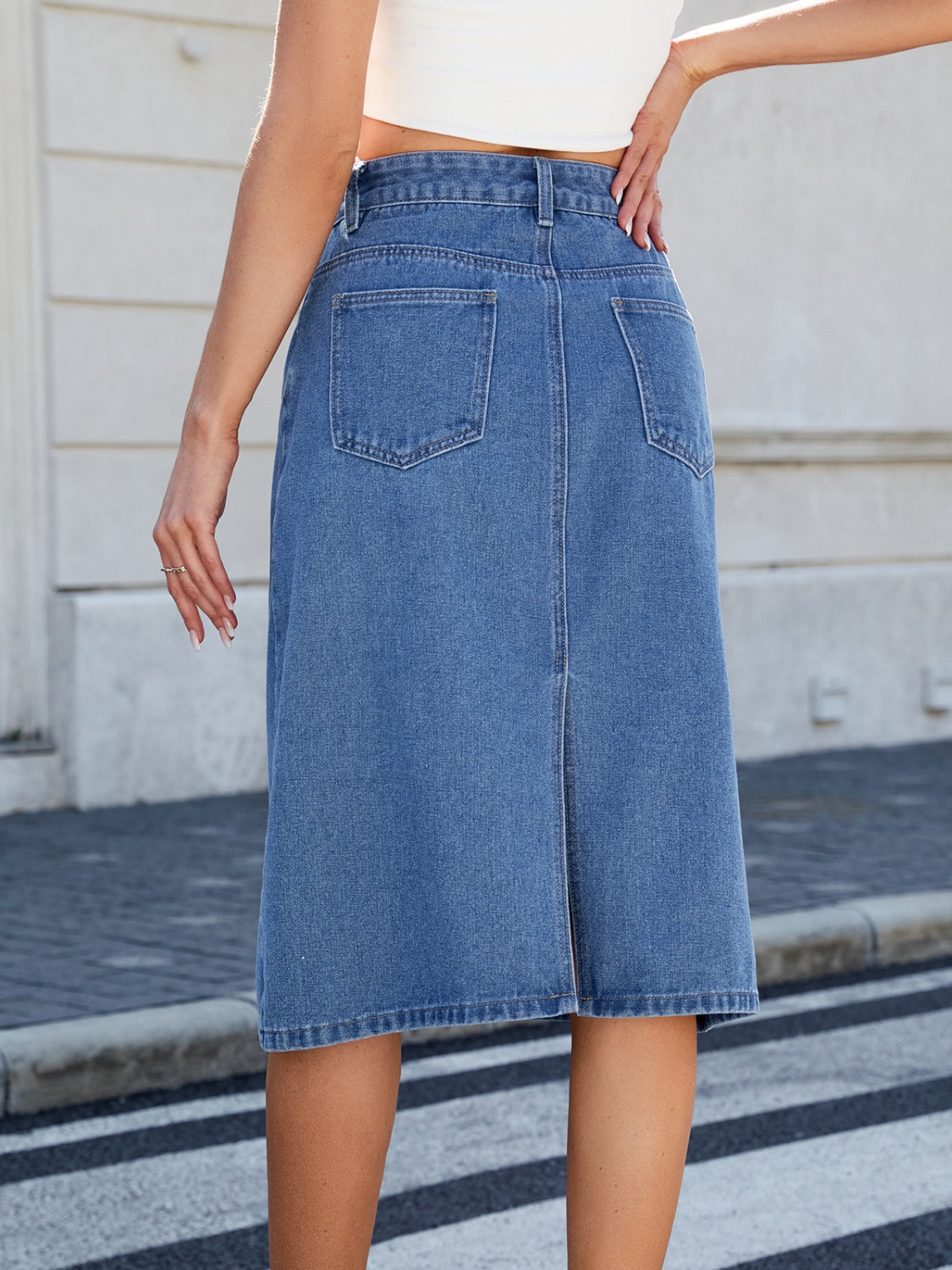 Panel-seam denim midi skirt in light blue with back pockets and a vent.