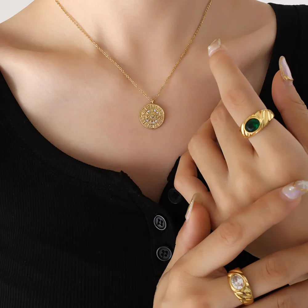 Gold zodiac compass pendant necklace with celestial details on a delicate chain.