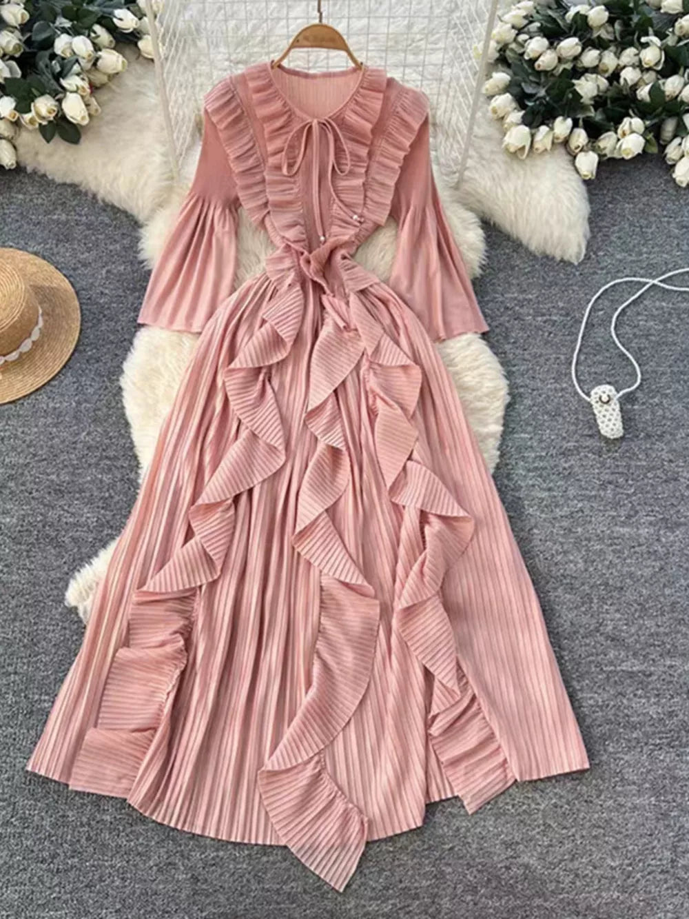 Pink midi dress with cascading ruffles, tie neck, and bell sleeves.