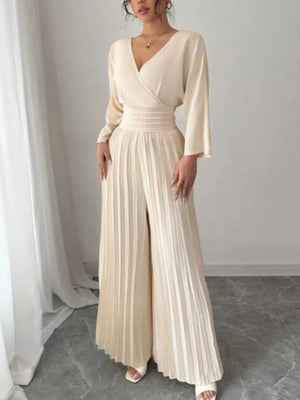 Beige wide-leg jumpsuit with V-neck, cinched waist, and pleated palazzo pants.