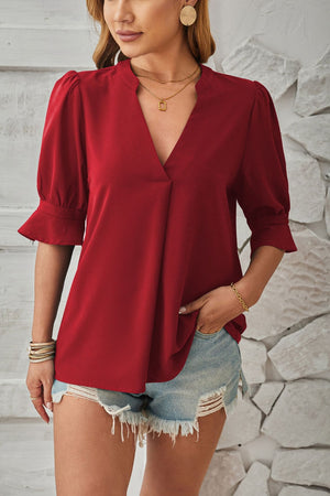 Burgundy blouse with puffed sleeves and flared cuffs, V-neck, and a draped front.