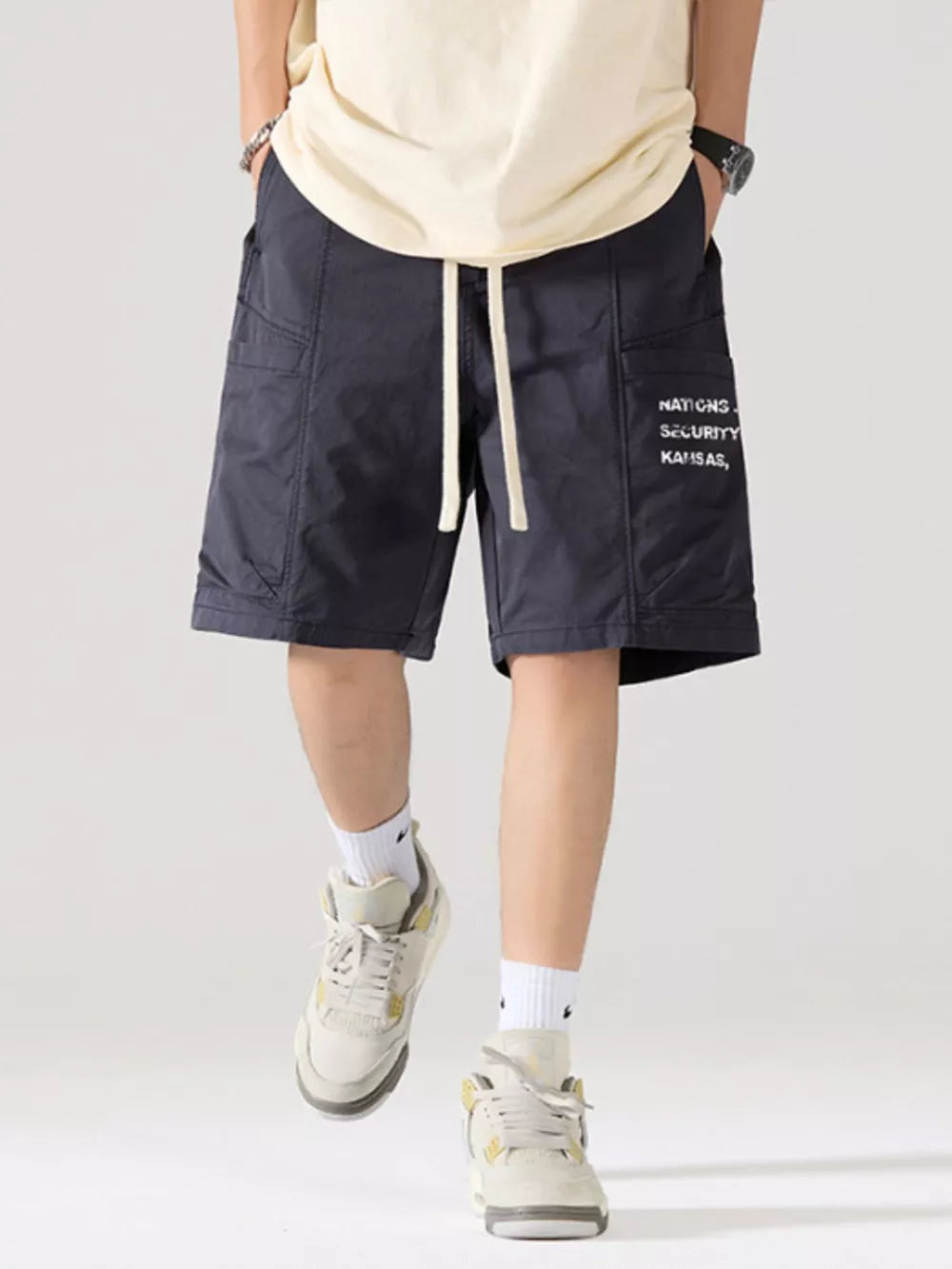 Navy blue cotton cargo shorts with adjustable drawstring and side pocket text detail.