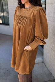 Caramel corduroy mini dress with puff sleeves, gathered neckline, and buttoned cuffs.