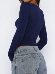 Navy long sleeve ruched crop top with a crew neck, styled with denim jeans.