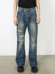 Distressed flare leg jeans in medium wash denim with ripped details.