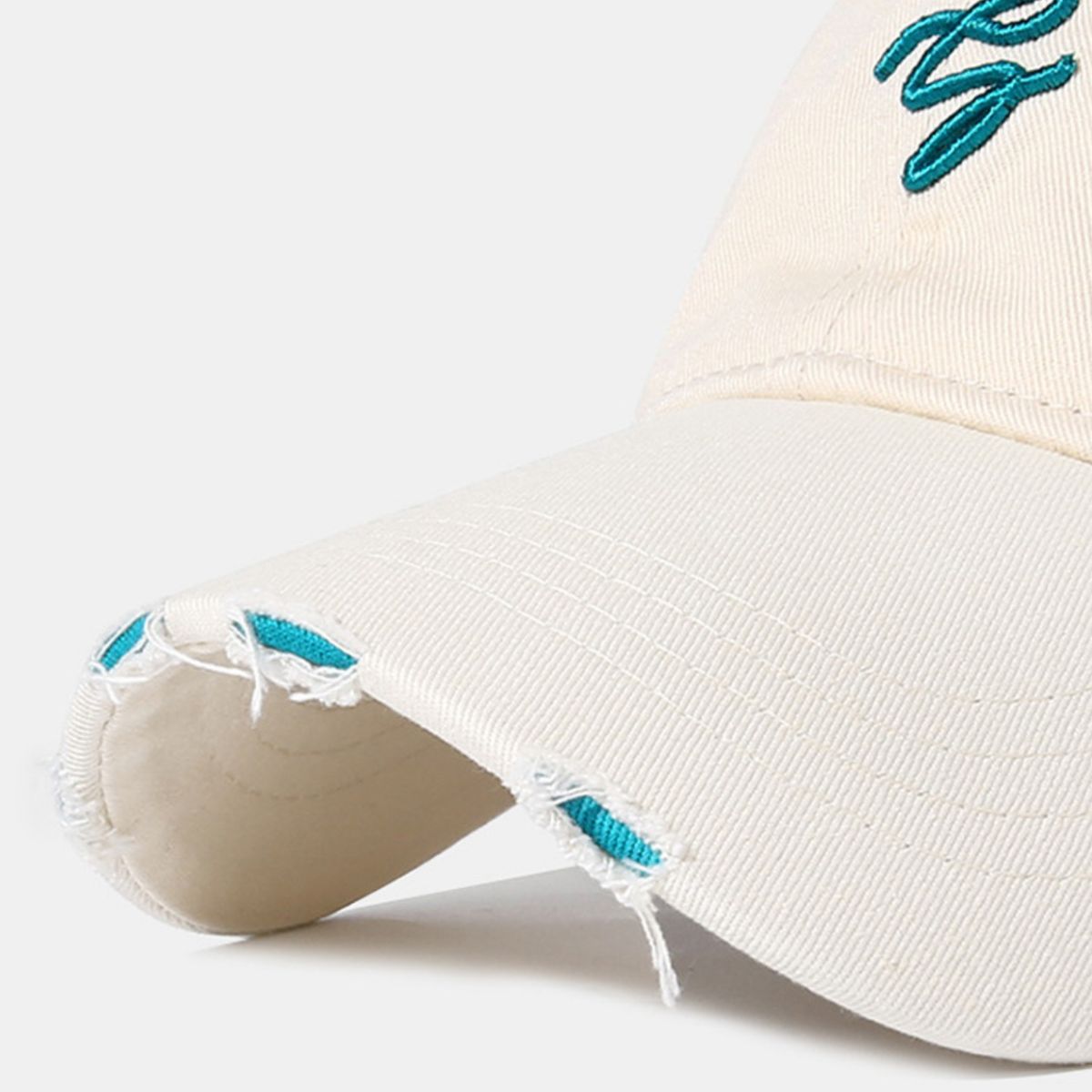 Off-white distressed cotton baseball cap with teal embroidery and frayed details.