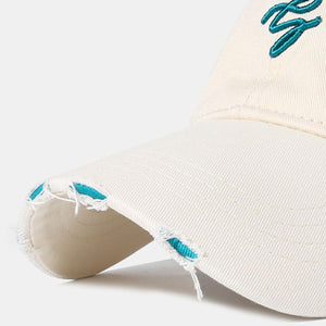Off-white distressed cotton baseball cap with teal embroidery and frayed details.