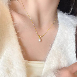 Gold pearl pendant necklace with knot detail on a delicate chain.