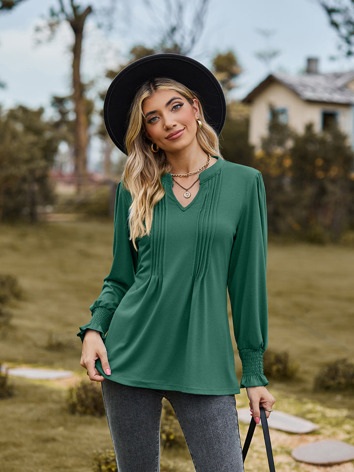 Green long sleeve blouse with V-neck, pleated yoke, and shirred cuffs.