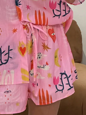 Pink co-ord pajama set with a whimsical print of celestial bodies, flowers, and eyes.