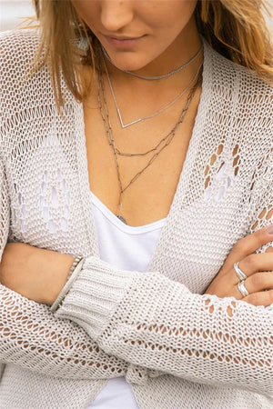 Beige open-knit acrylic cardigan with slit hem detail.