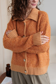 Textured bouclé collar cardigan in tangerine with button front and ribbed cuffs and hem.