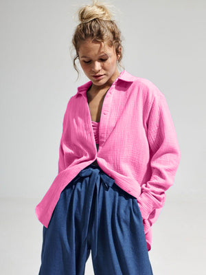 Textured cotton overshirt in hot pink with relaxed fit and button front, styled open over a bralette.